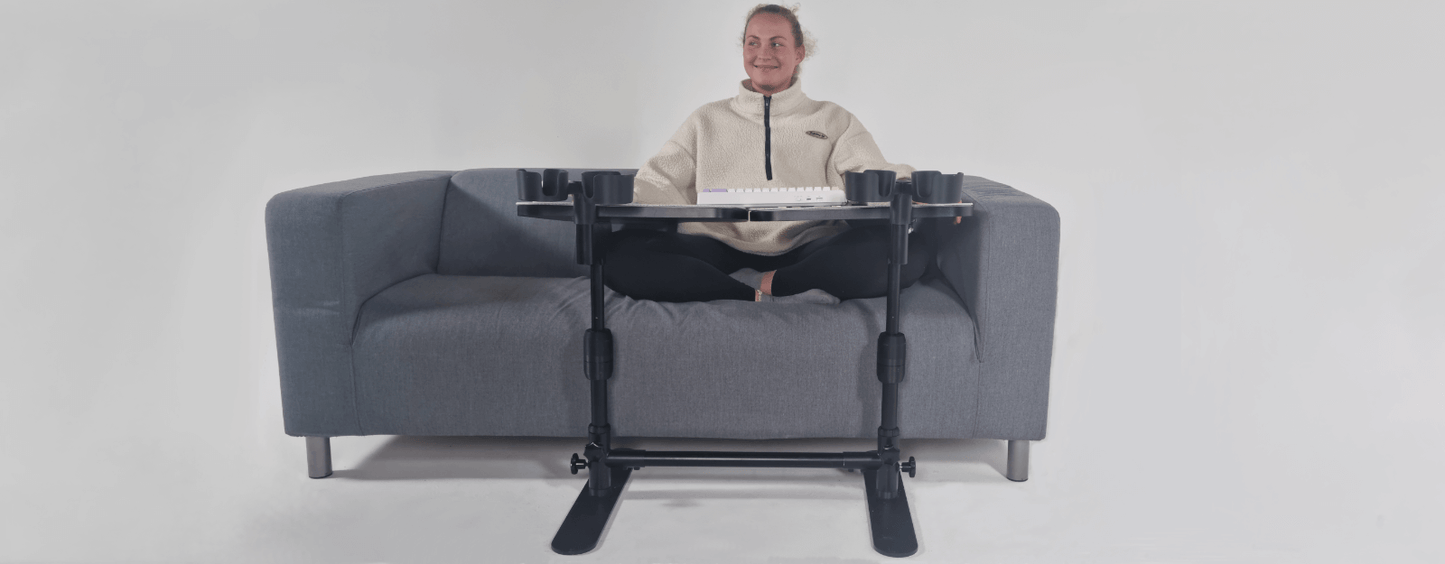 Woman sitting on a sofa using a sofa workstation for ergonomic home office setup.